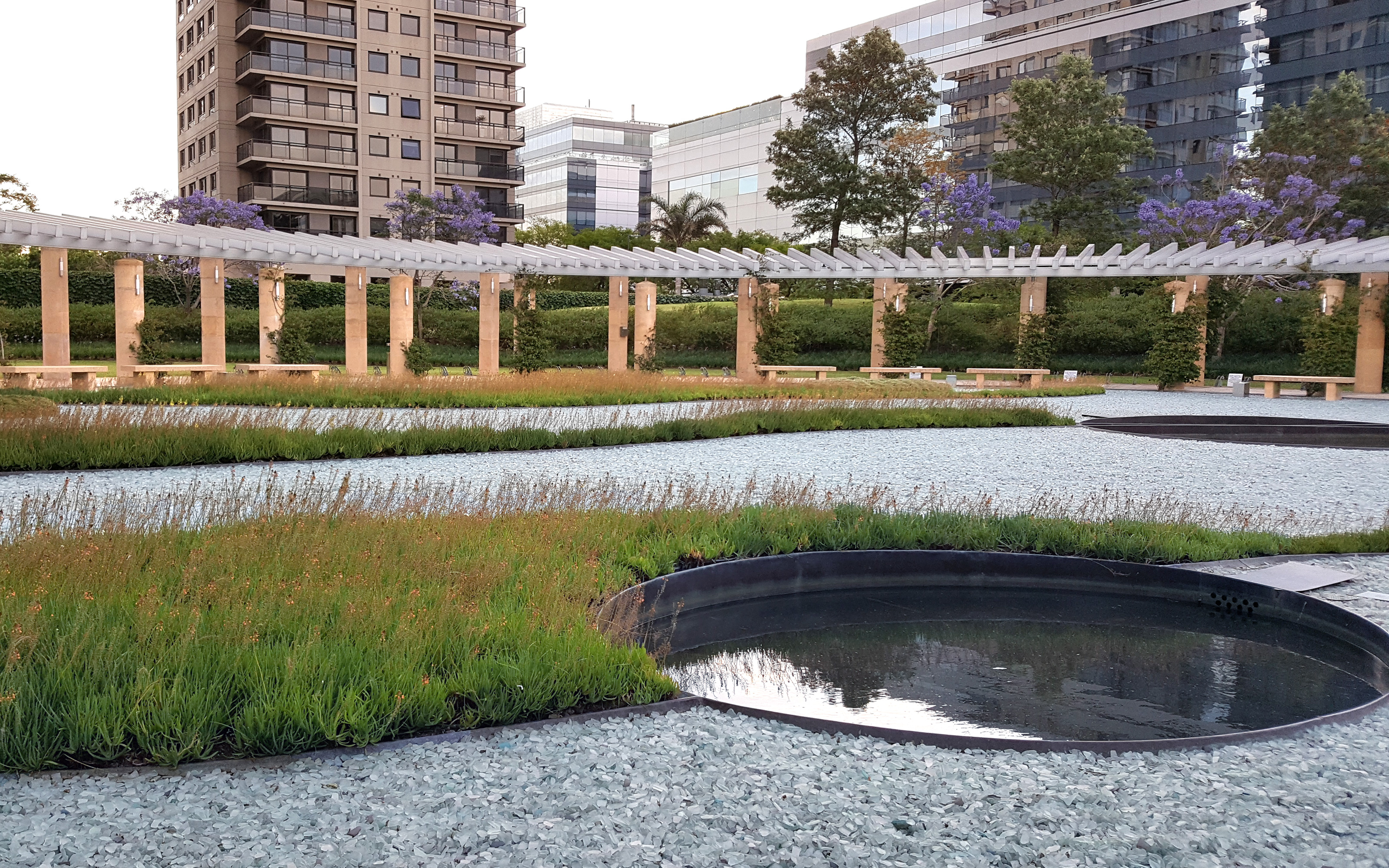 Garden with glass gravel, circular water basin and plant beds